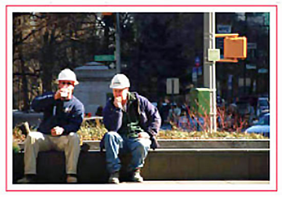 Two workers in hard hats seated at an outdoor worksite